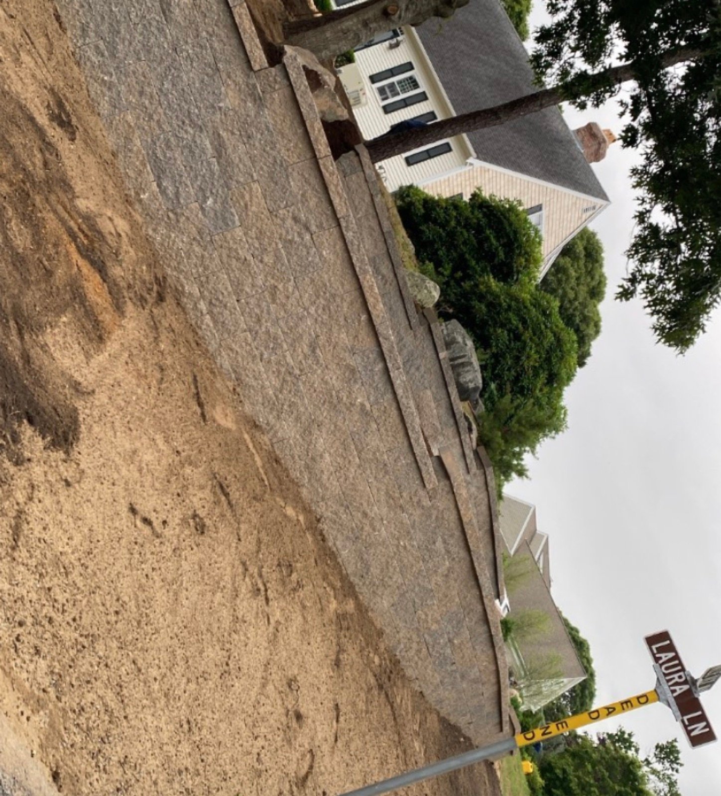 A bare cut slope with nothing holding it back, the condition a retaining wall is built to fix