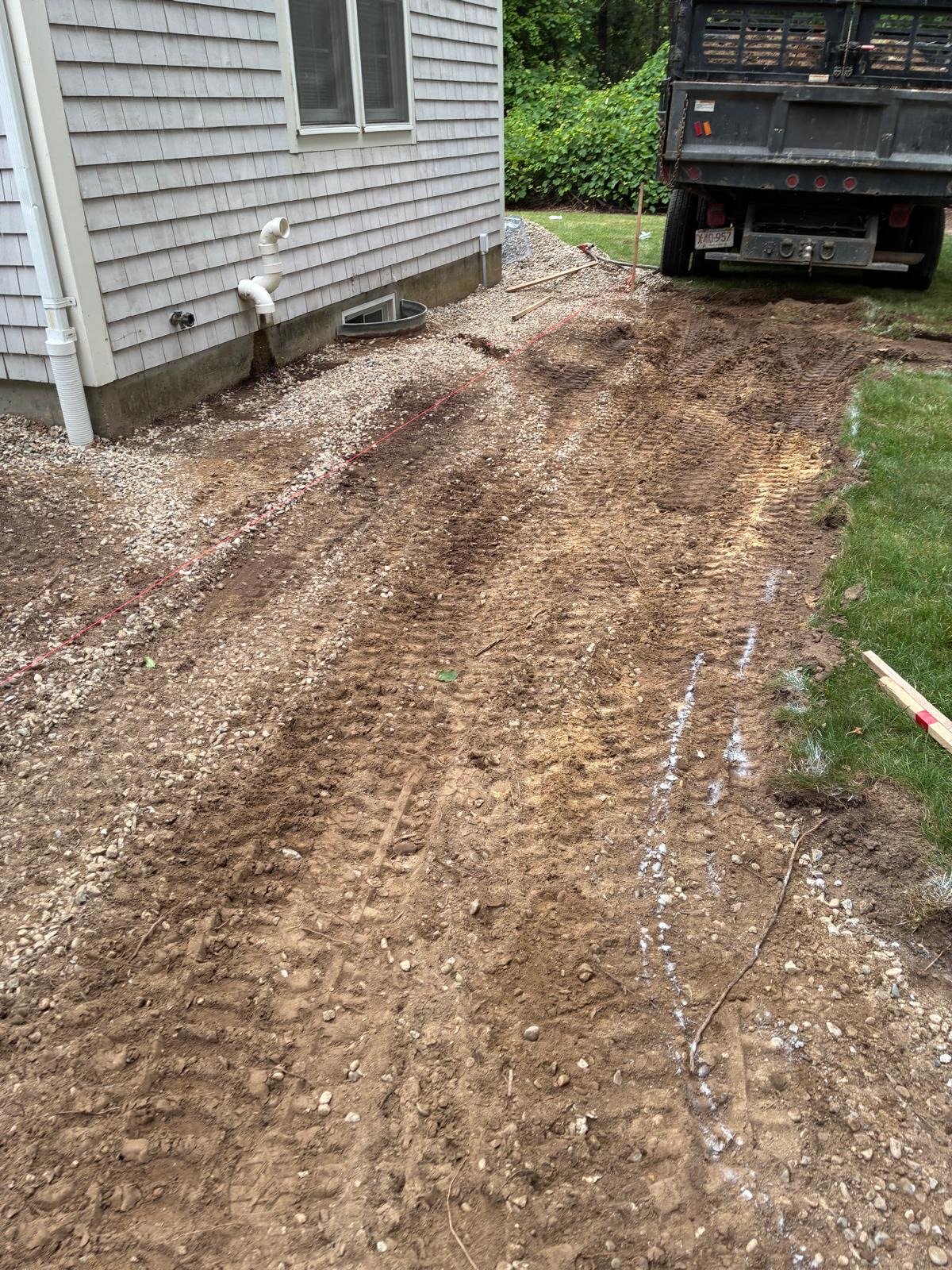 Bare sandy Cape Cod soil graded flat before any planting or hardscape goes in