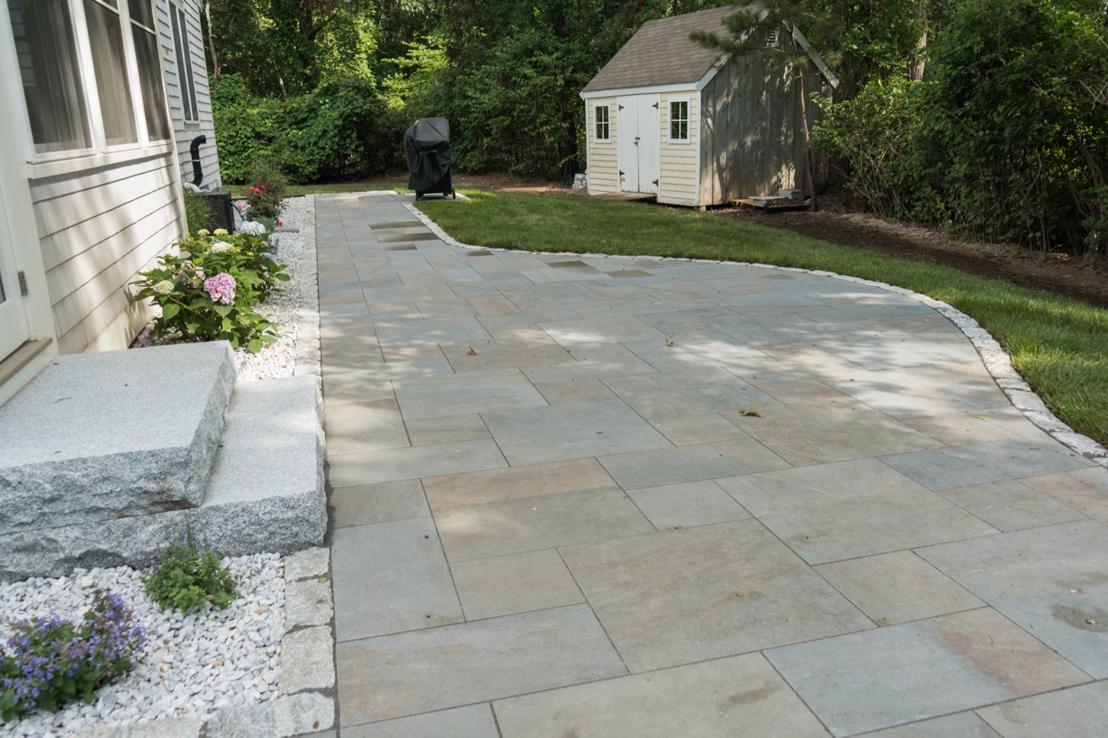 Bluestone patio laid to a granite step and a planted gravel border