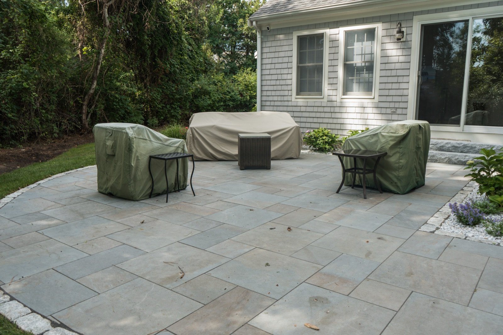 Bluestone patio with a seating area set against a shingled house wall