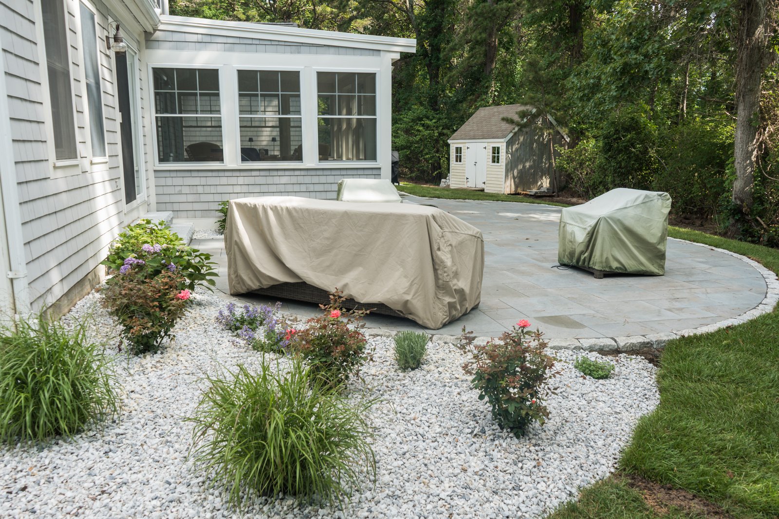 The same Brewster back yard finished with a bluestone patio, cobble border and planted beds in white stone