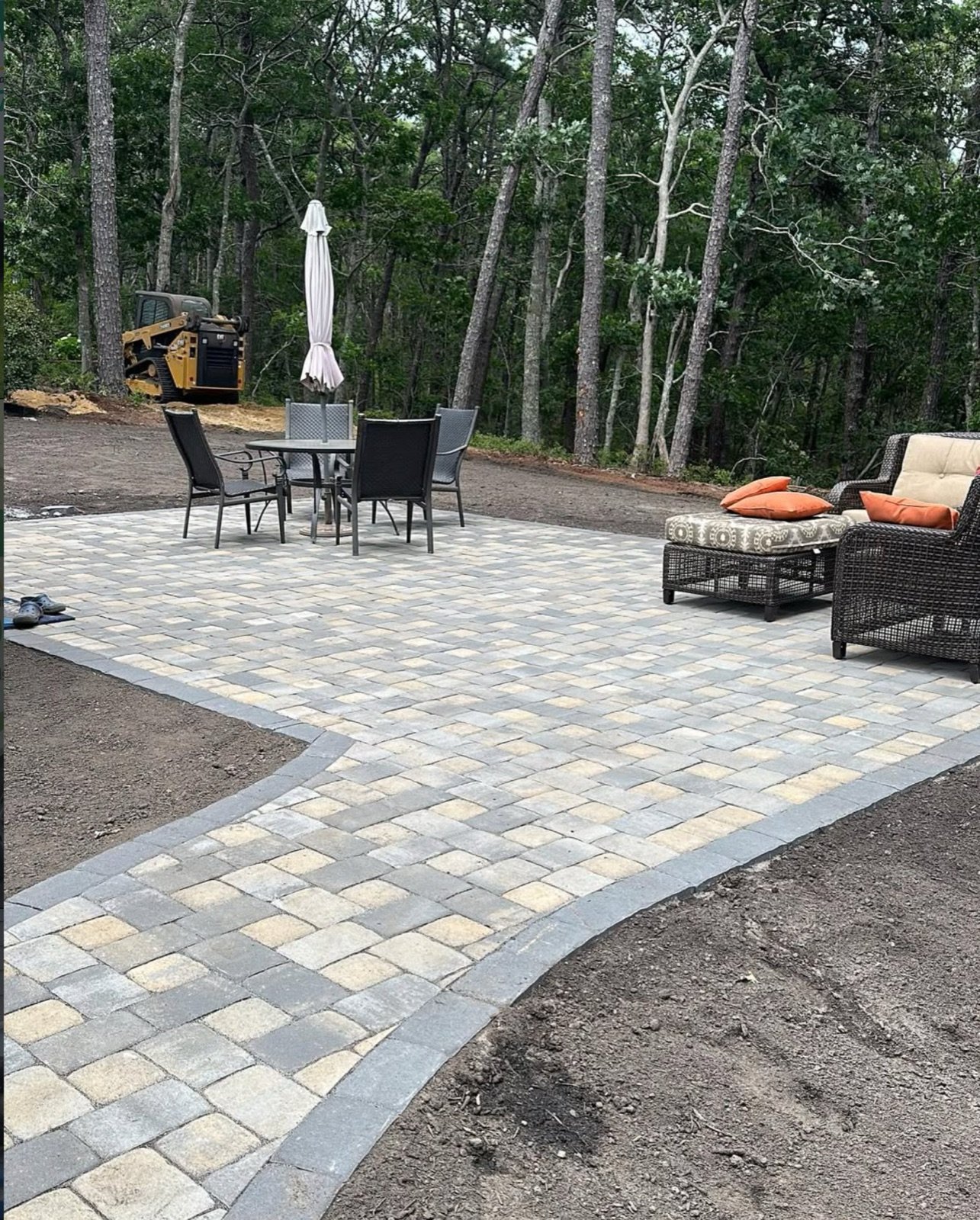 Concrete paver patio laid out with outdoor furniture at the back of a Cape Cod property
