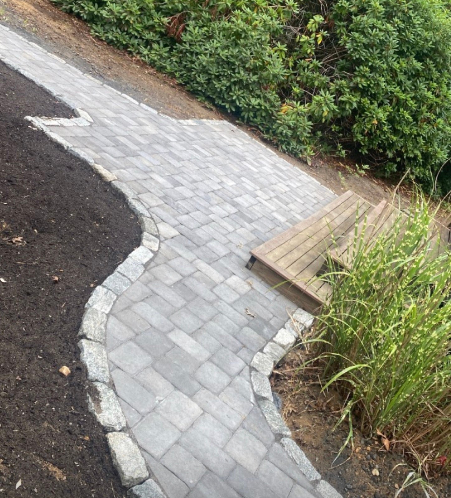 Concrete paver walkway with a contrasting border curving across a lawn