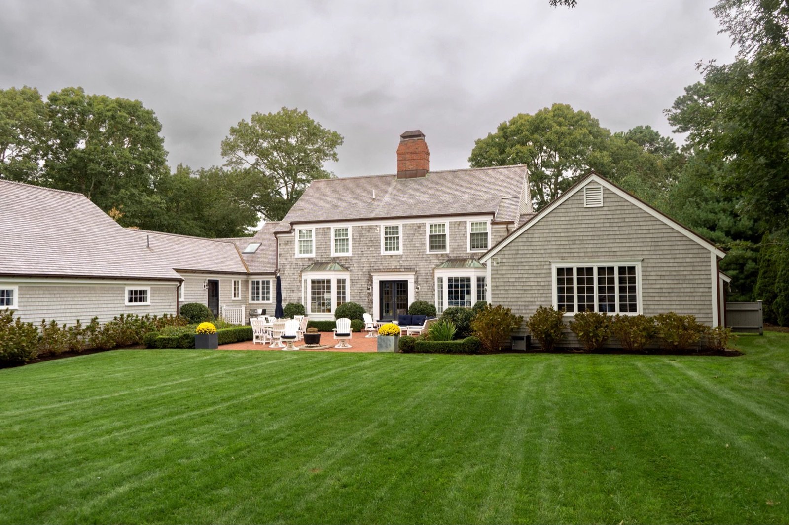 A Cape Cod property with a designed front lawn, clipped foundation planting and mulched beds
