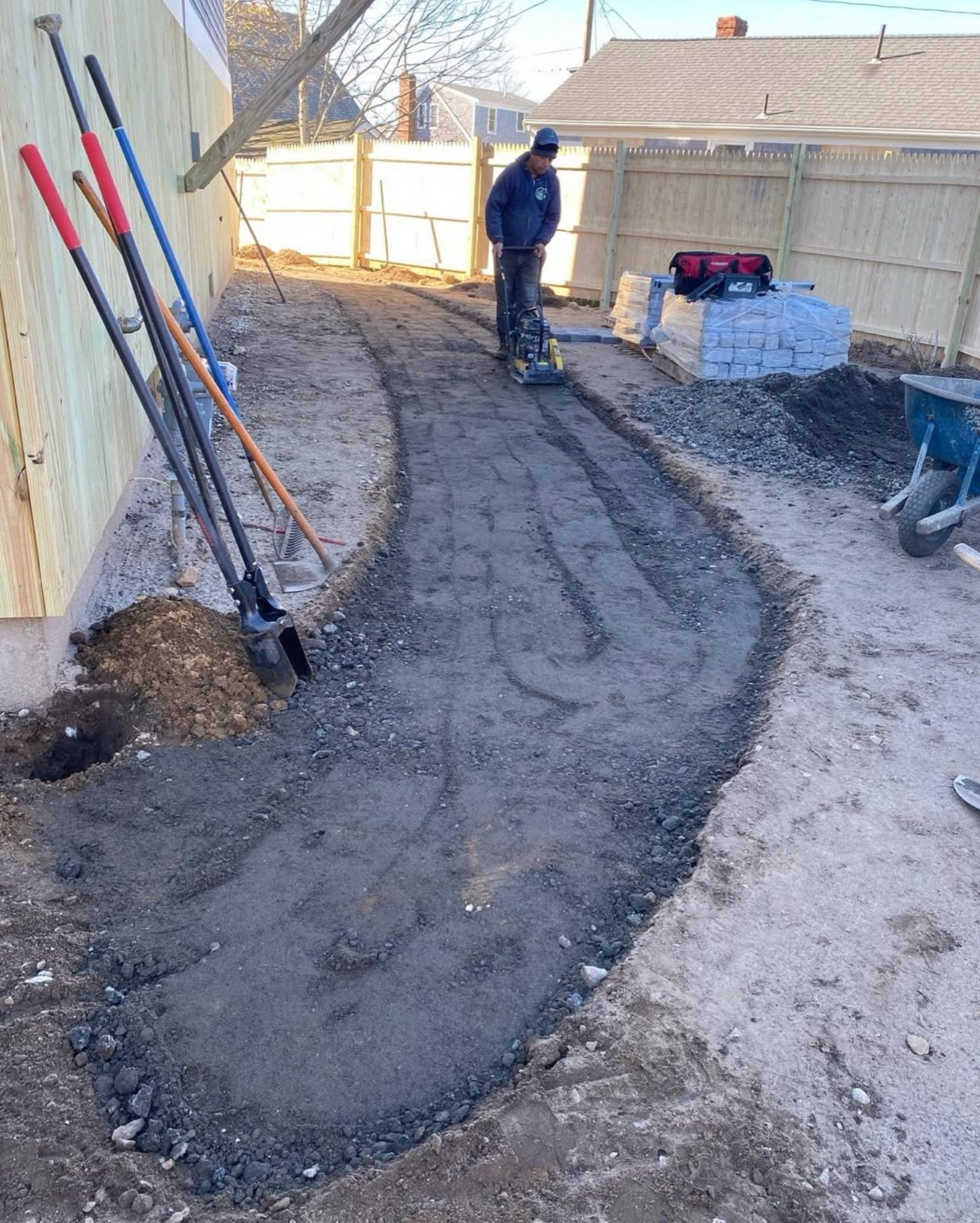 A curved trench excavated for drainage and base material before a surface is built