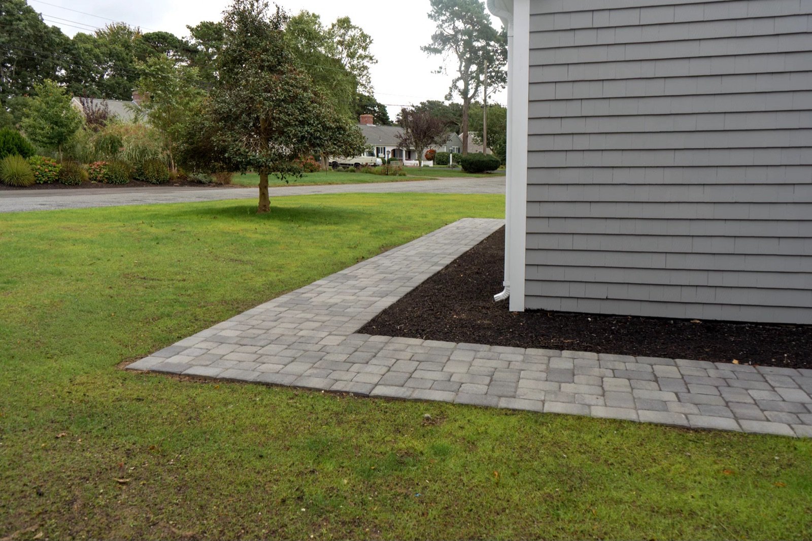 A finished paver walkway with clean, tight joints running beside a lawn