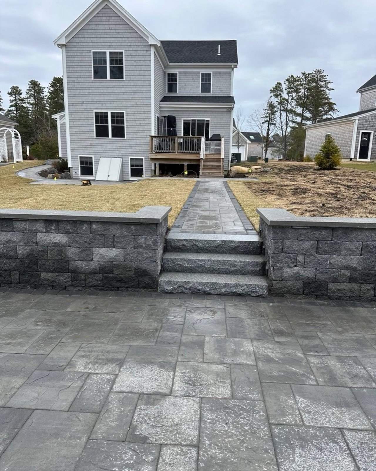 Granite steps between block seat walls leading to a bluestone patio in South Yarmouth, MA