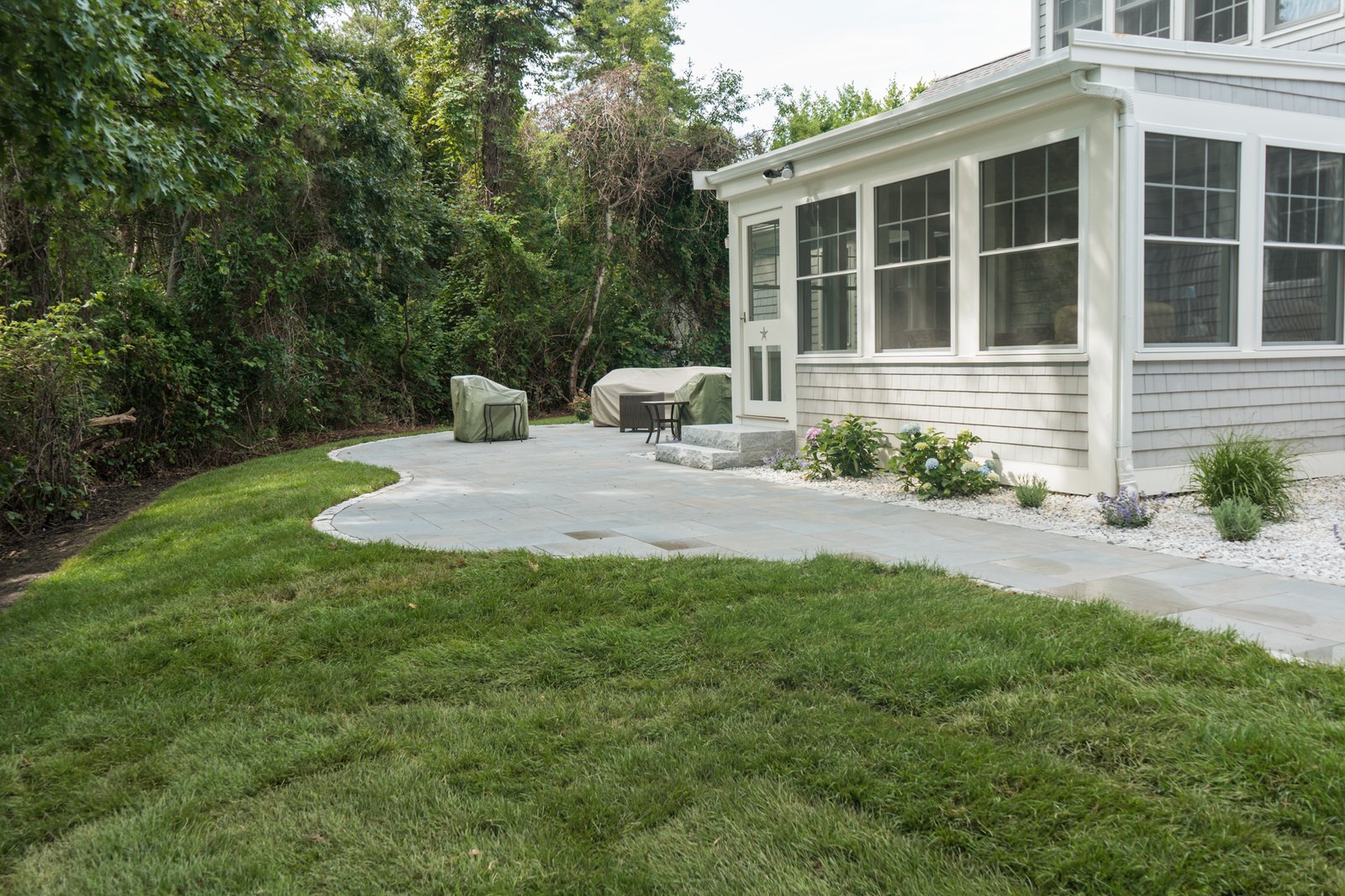 Finished bluestone patio and restored lawn outside the sunroom of a Brewster, MA home