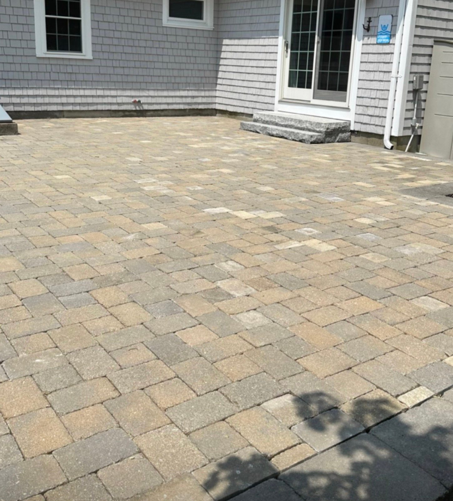 A finished paver patio laid in a running bond across a back yard