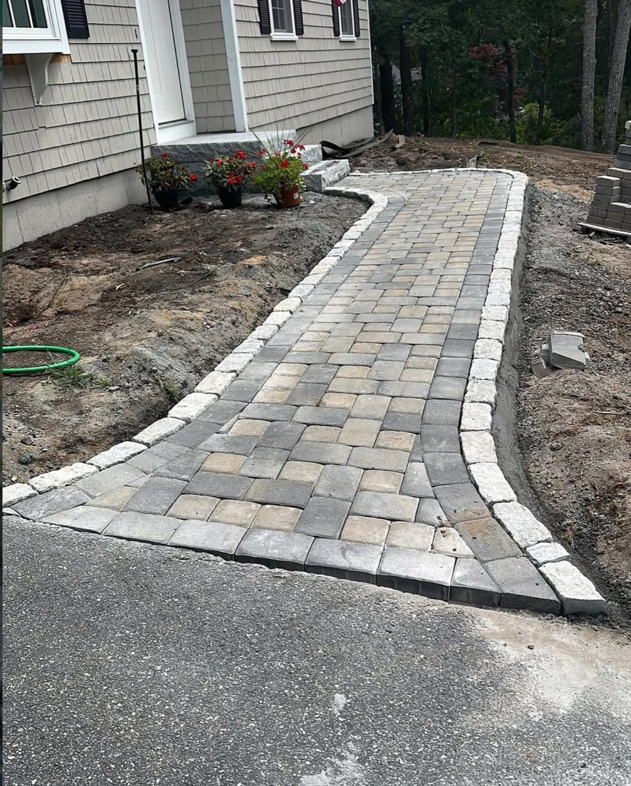 A paver walkway going in over a compacted base with the border course set first