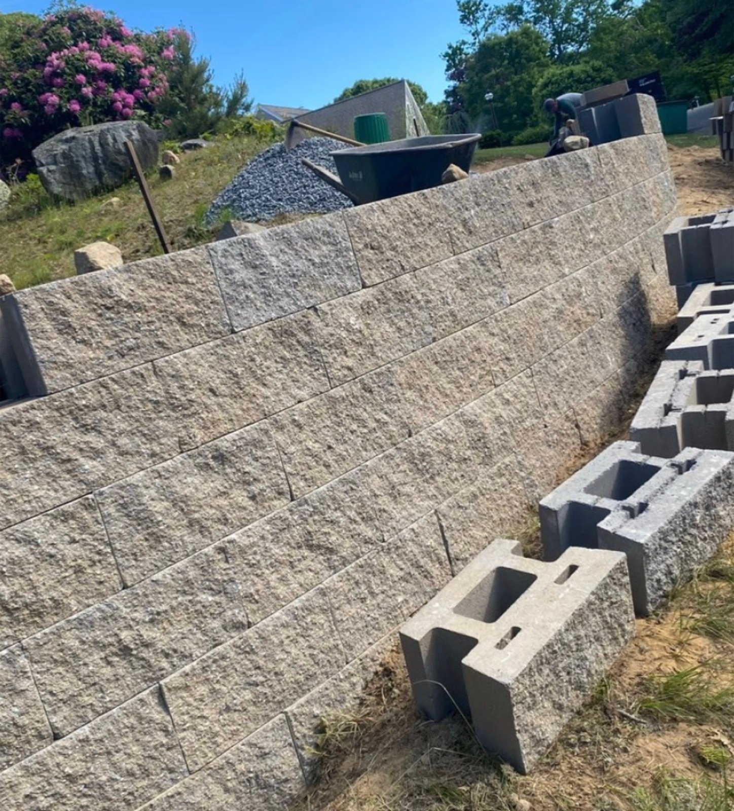 Segmental concrete block retaining wall going up course by course on a Cape Cod slope