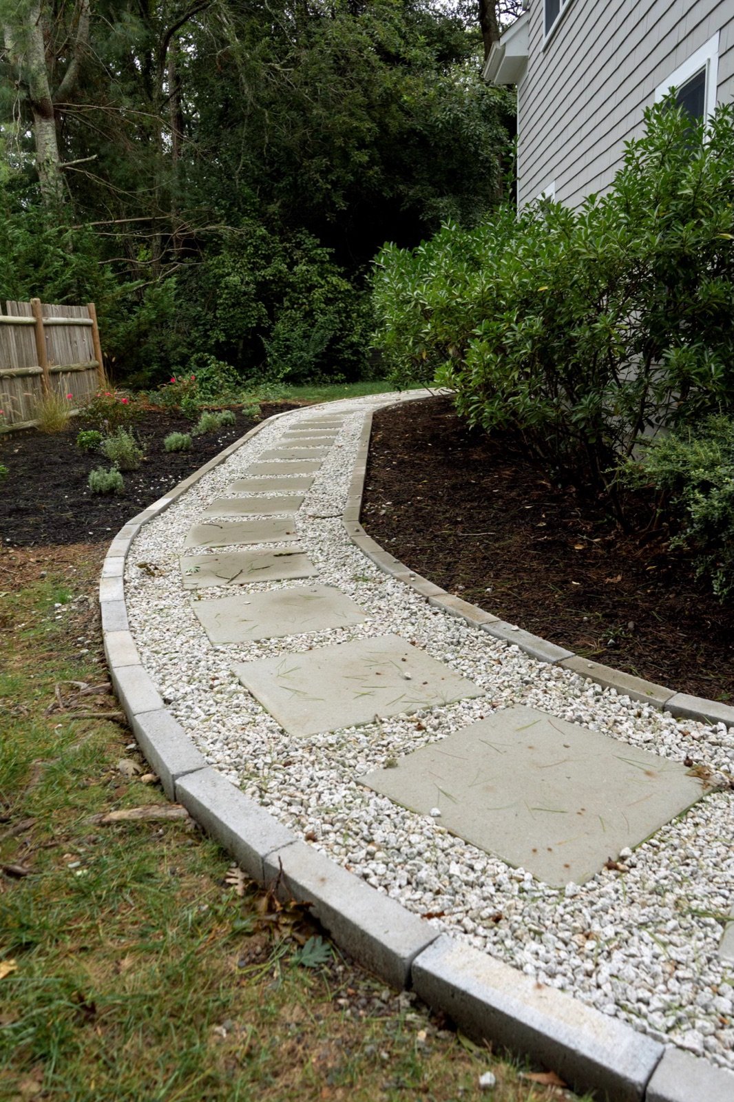 A stone path with a granite edge running through white gravel, showing the material mix