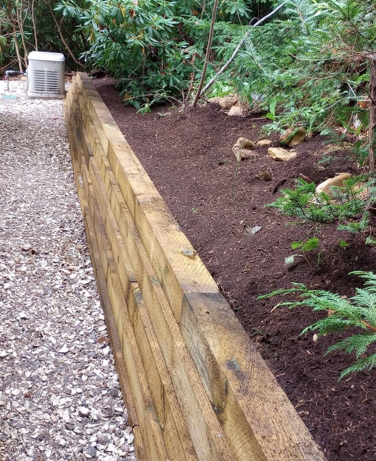 Pressure treated timber retaining wall holding a mulched planting bed